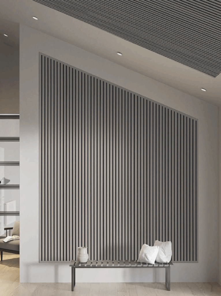 Moderner, minimalistischer Innenraum mit grauer Bank, Kissen, Vase und vertikalen Lamellen an der Wand.