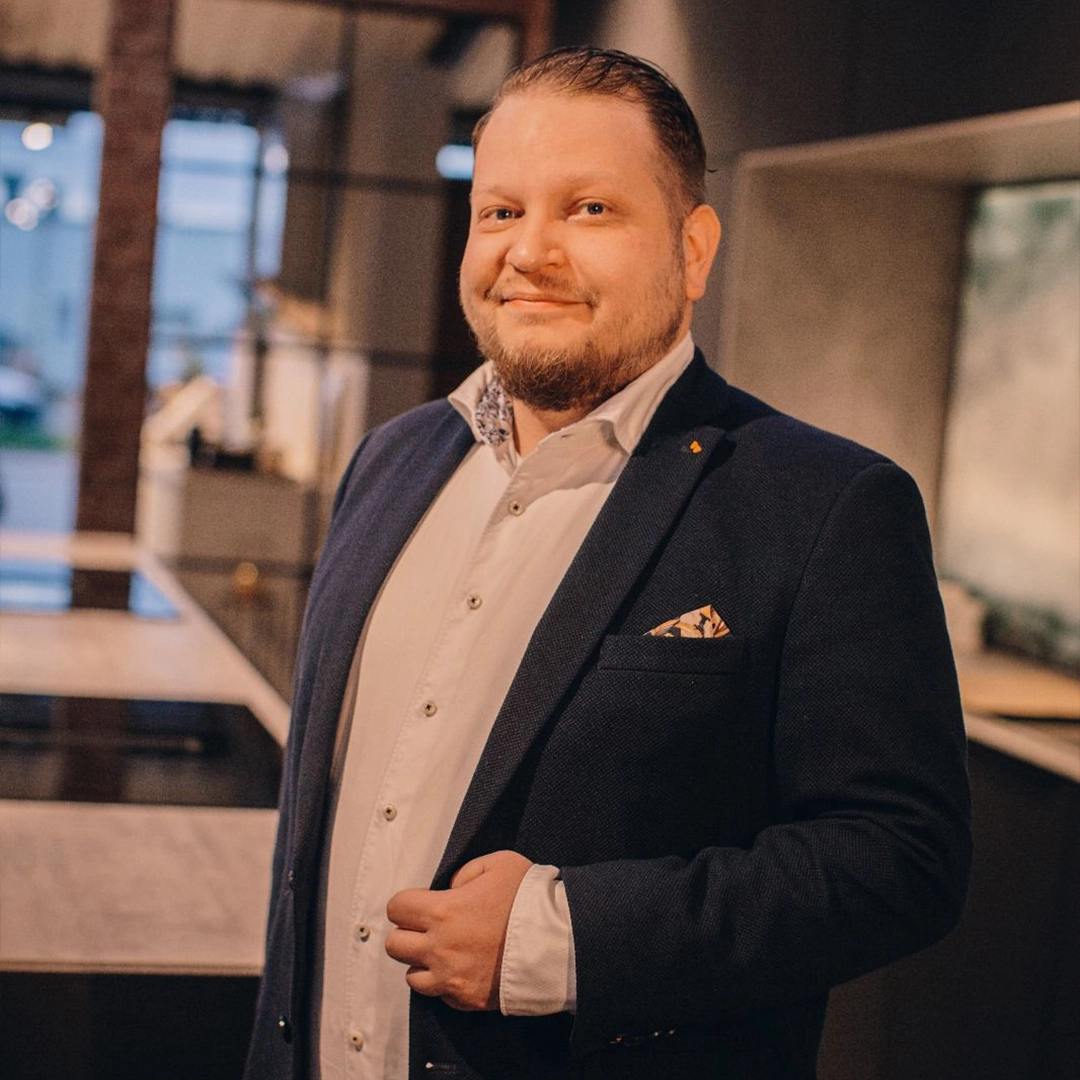 Person in dunklem Anzug in modernem, stilvollem Innenraum, warme Beleuchtung, professionelle Atmosphäre.