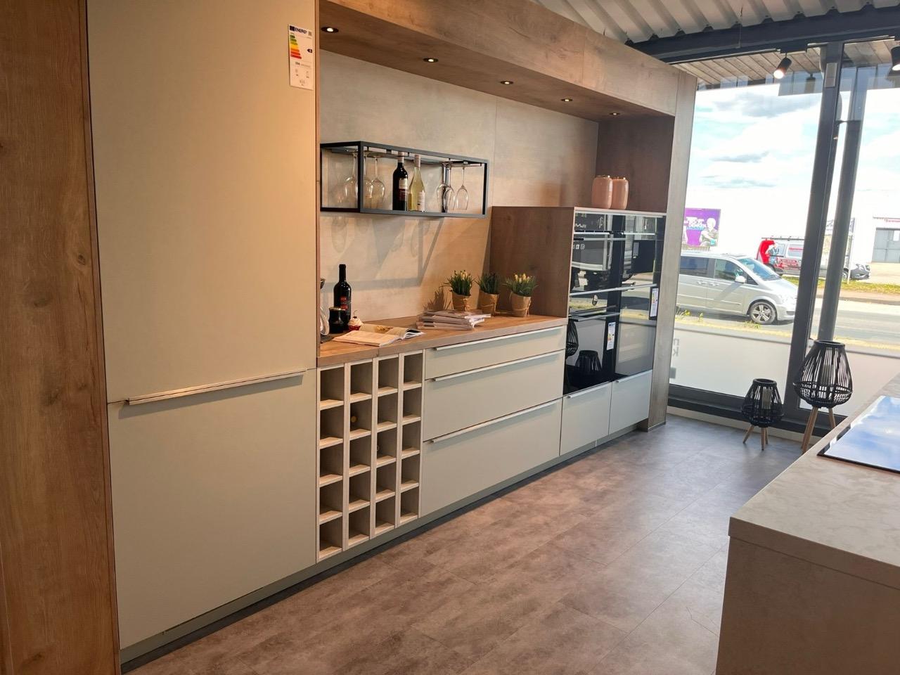 Moderne Küchenzeile in Beige mit Holzdetails, integriertem Weinregal und dekorativen Pflanzen.