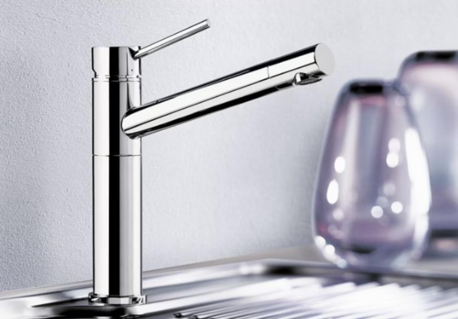 Moderner, verchromter Wasserhahn mit schlankem Design vor unscharfem Hintergrund aus Gläsern.