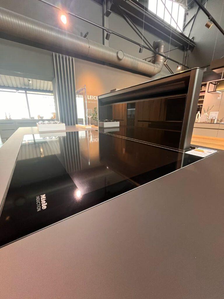 Moderne Küche mit Miele Induktionskochfeld, umgeben von eleganten, glatten Möbeln in neutralen Tönen.