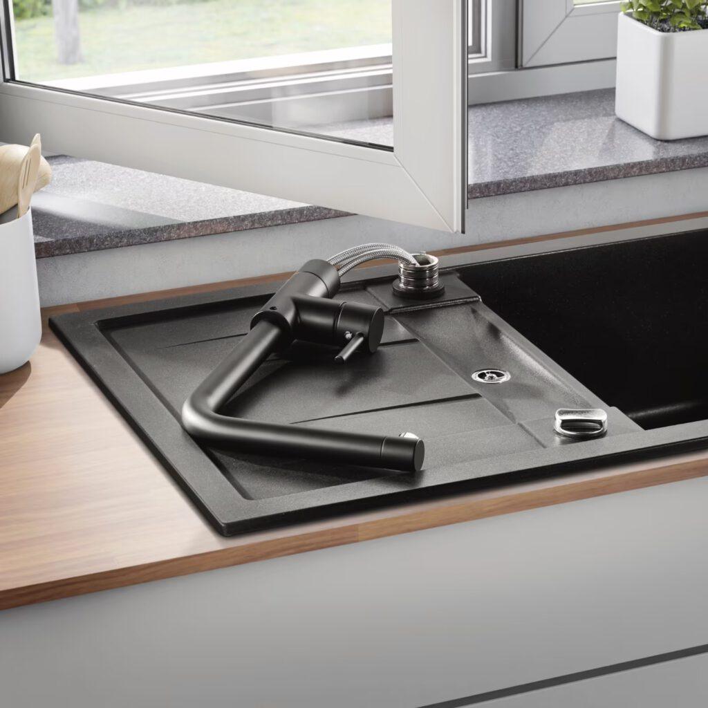 Moderne Küche mit unmontierter schwarzer Armatur auf schwarzer Spüle, Tageslicht durch offenes Fenster.