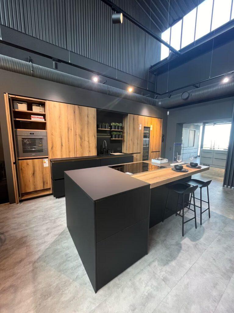 Moderne Küche mit schwarzem Küchenblock, Holzarbeitsplatte und industriellem Design in Grau und Braun.