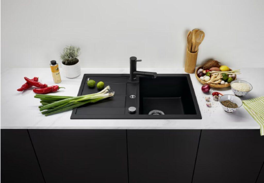 Moderne Küche mit bunter Gemüseauswahl, Reis und Gewürzen auf weißer Arbeitsplatte neben schwarzer Spüle.