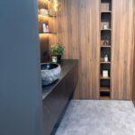 Modernes Badezimmer mit steinernem Waschbecken, hölzernem Schrank und goldener Lampe in warmem Licht.