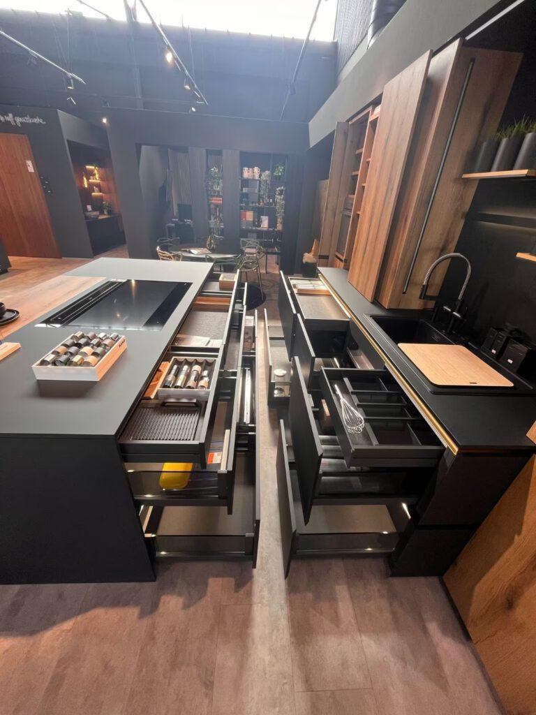 Moderne Küche mit offenen Schubladen, die Kochutensilien zeigen; elegante, dunkle und warme Holzfarben.