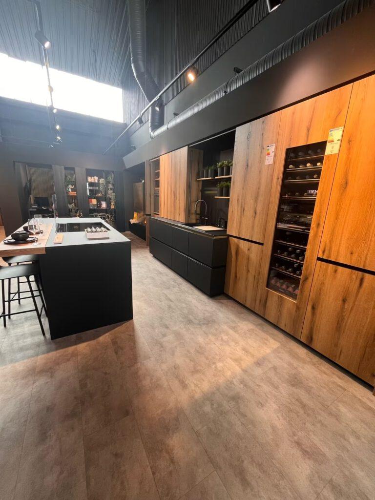 Moderne Küche mit dunkler Insel, hölzernen Schränken und Metallakzenten in stilvollem, minimalistischem Design.