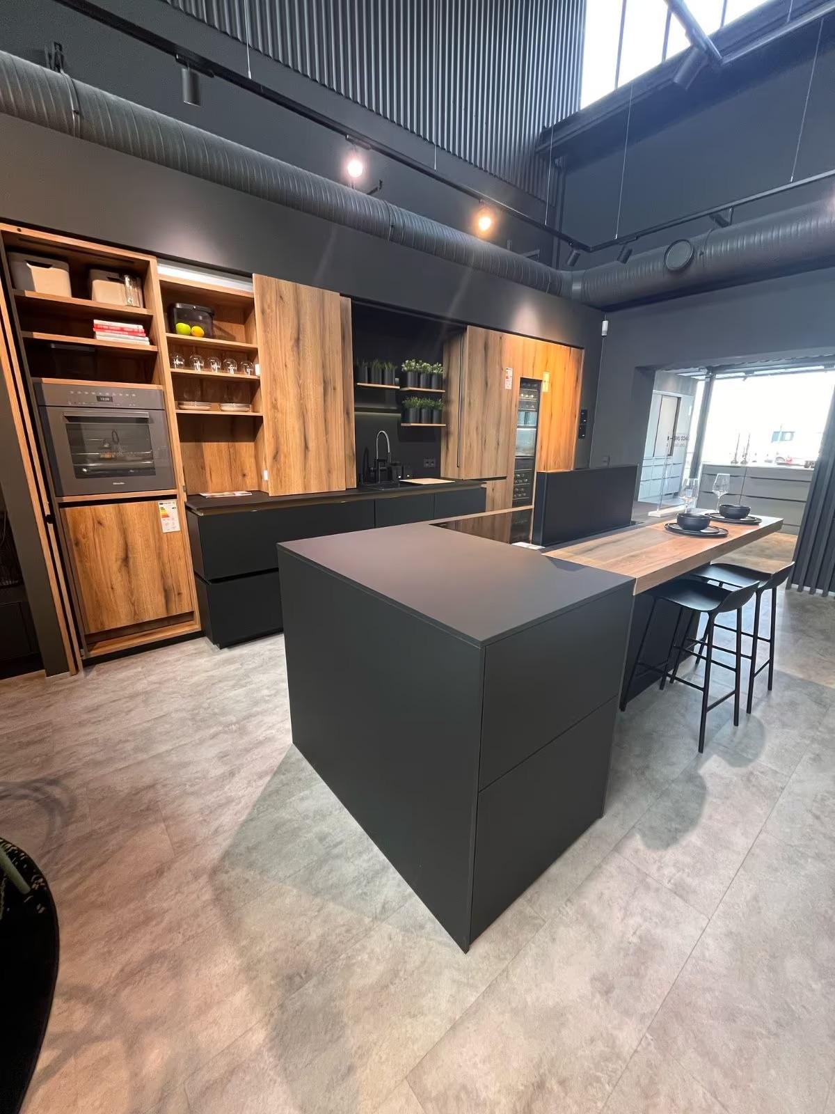 Moderne, minimalistische Küche mit schwarzer Insel, Holzfronten und eleganten, industriellen Akzenten.