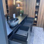 Modernes Badezimmer mit steinartiger Waschschüssel, warmem Licht und eleganten Holzakzenten.