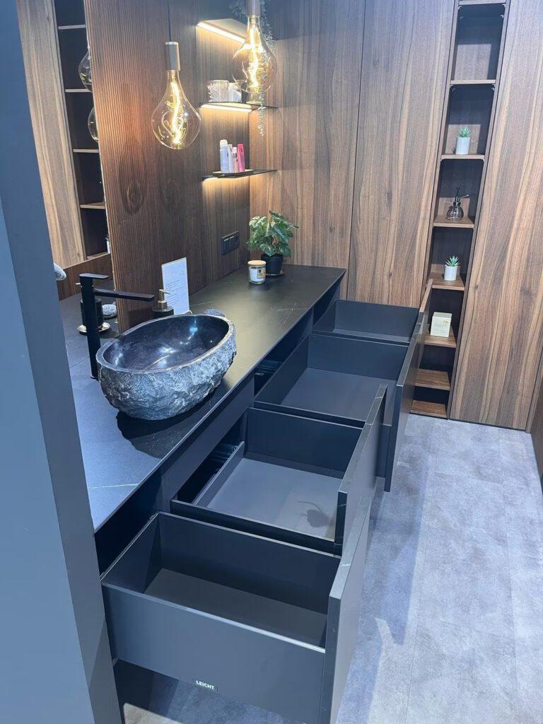 Modernes Badezimmer mit steinartiger Waschschüssel, warmem Licht und eleganten Holzakzenten.