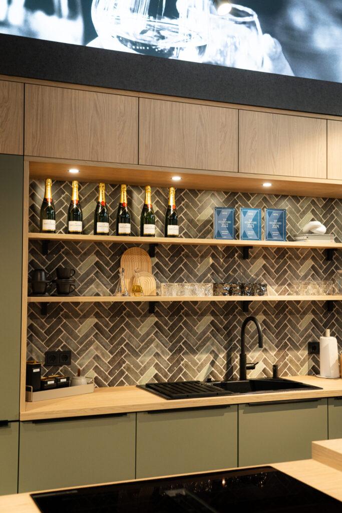 Moderne Küche mit Holzschränken, Champagnerflaschen, Tassen, Gläsern und einer eleganten Arbeitsfläche.