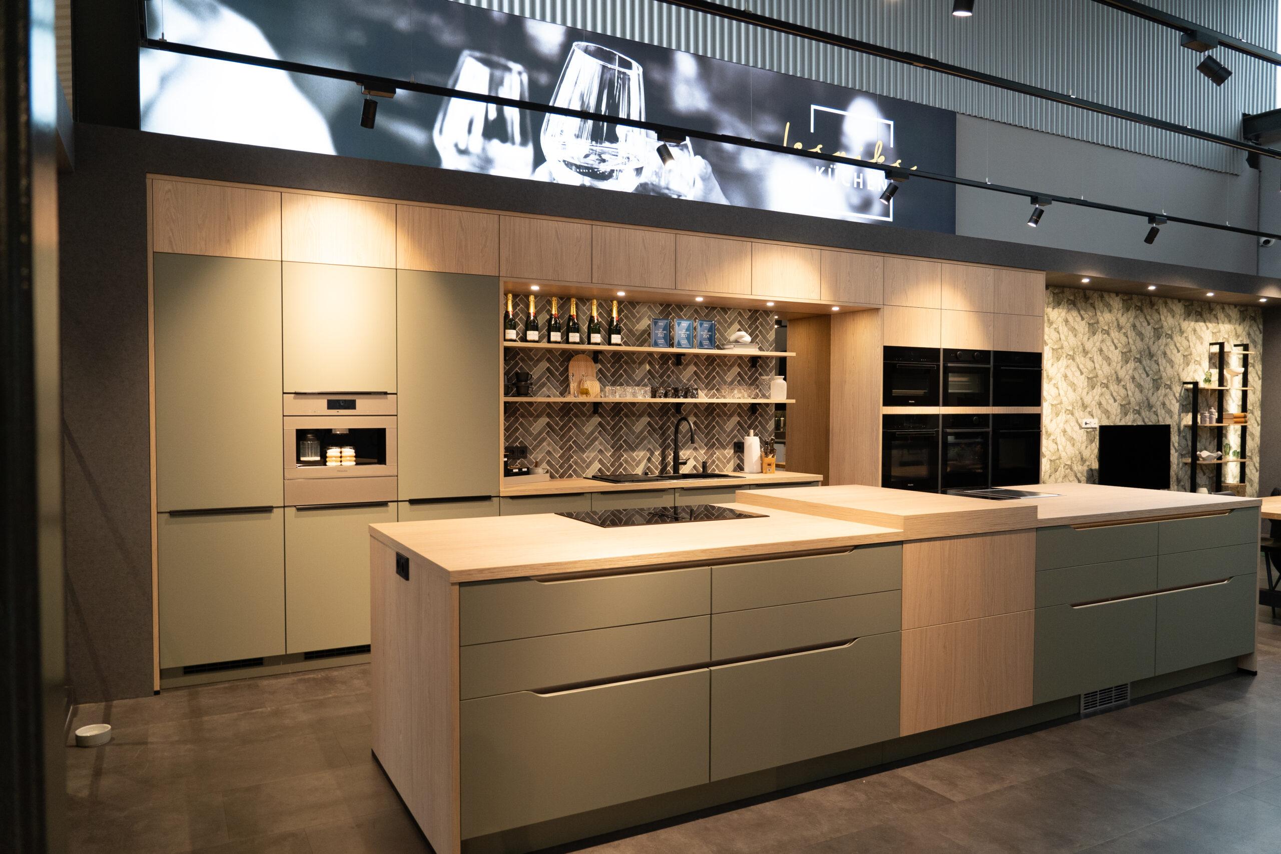 Moderne, stilvolle Küche mit Holz- und matten Oberflächen, zentralem Küchenblock und eingebauten Geräten.