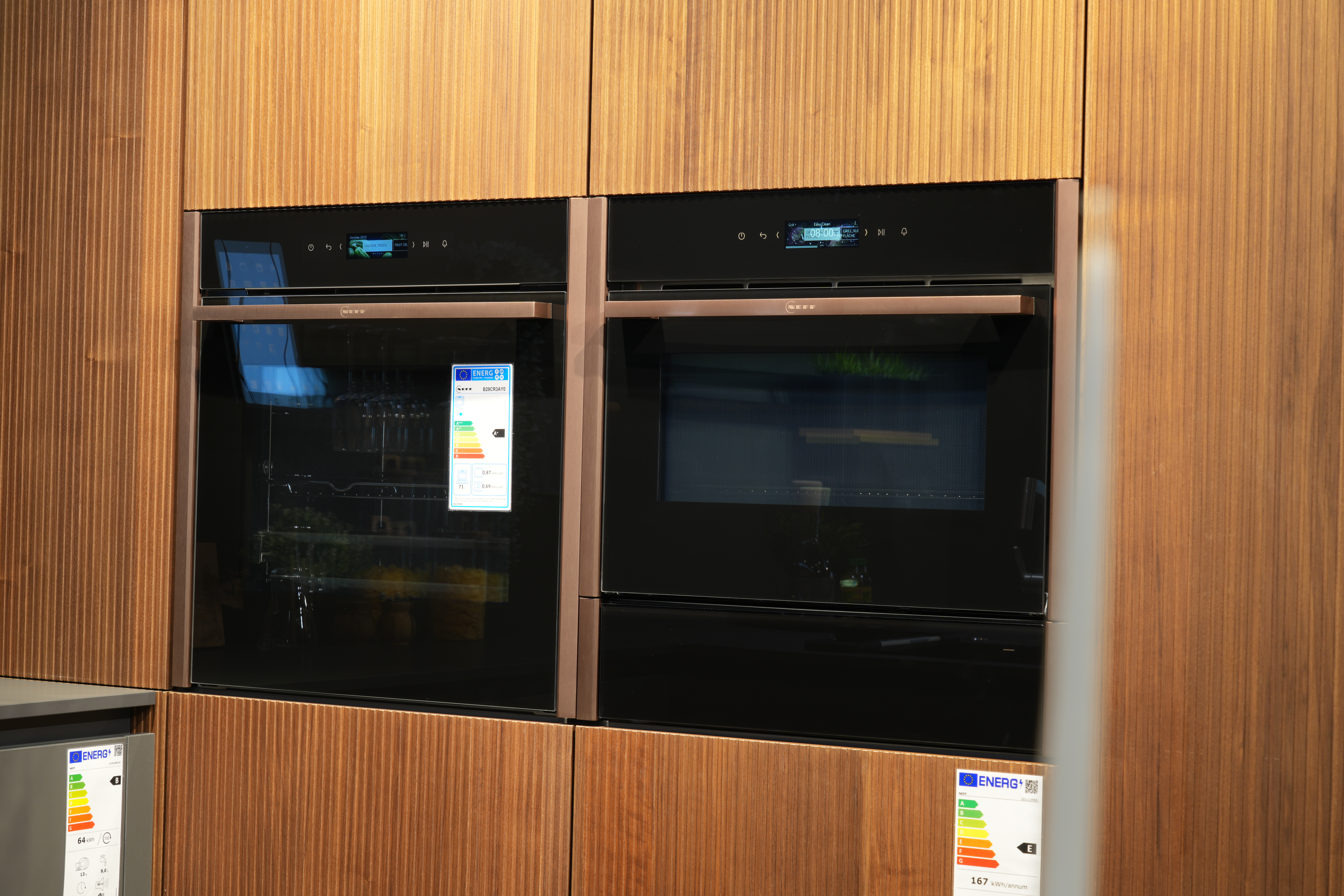 Moderne Küche mit zwei schwarzen, glänzenden Backöfen in einem warmen Holzschrank integriert.