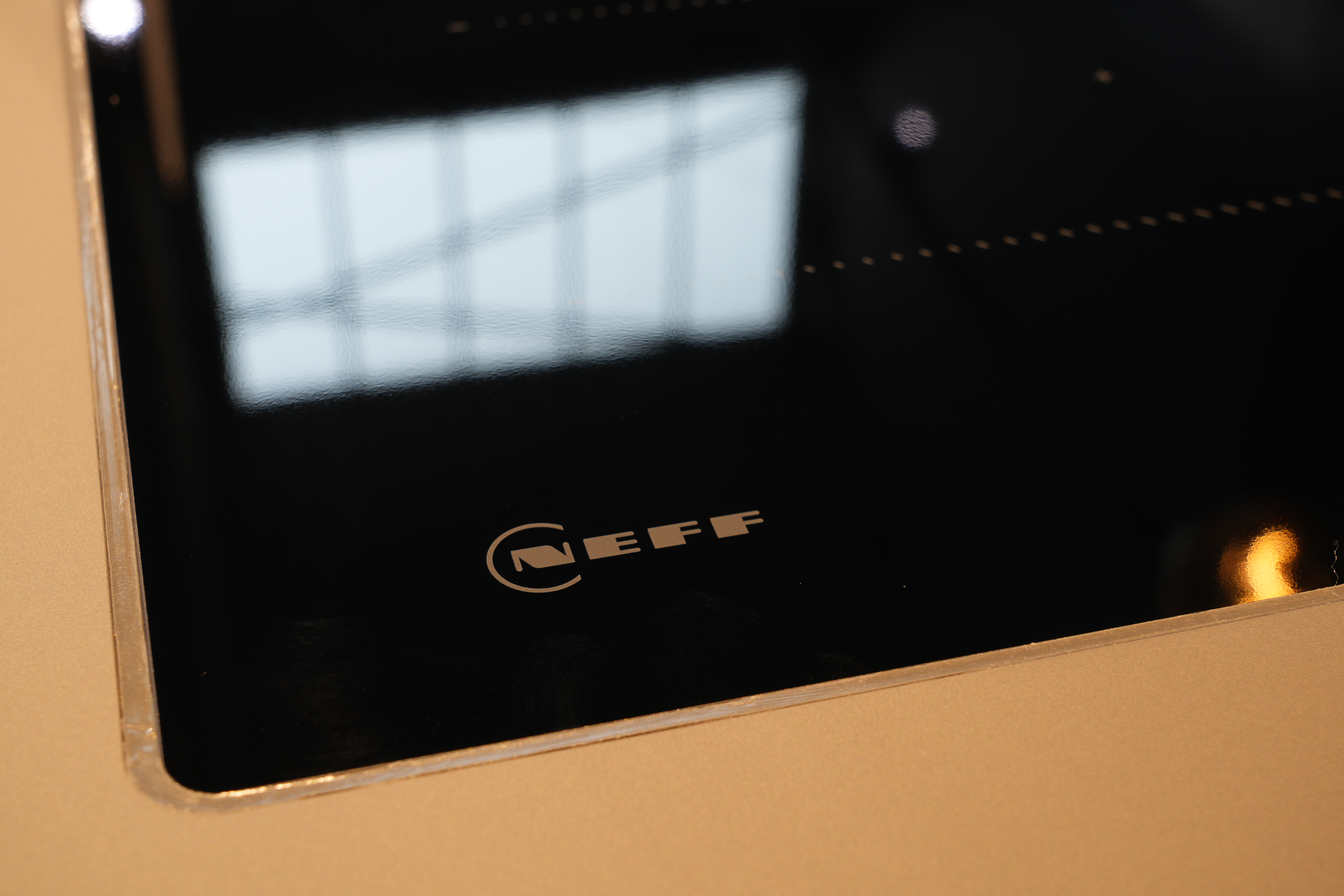 Nahaufnahme eines glänzenden, schwarzen NEFF Glaskeramik-Kochfelds in einer modernen Küche.