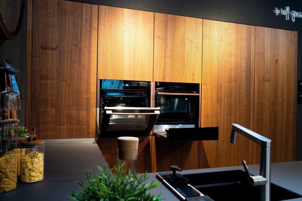 Moderne Küche mit Holzverkleidung, offenem Backofen, Glasbehältern und einer Pflanze als Dekoration.