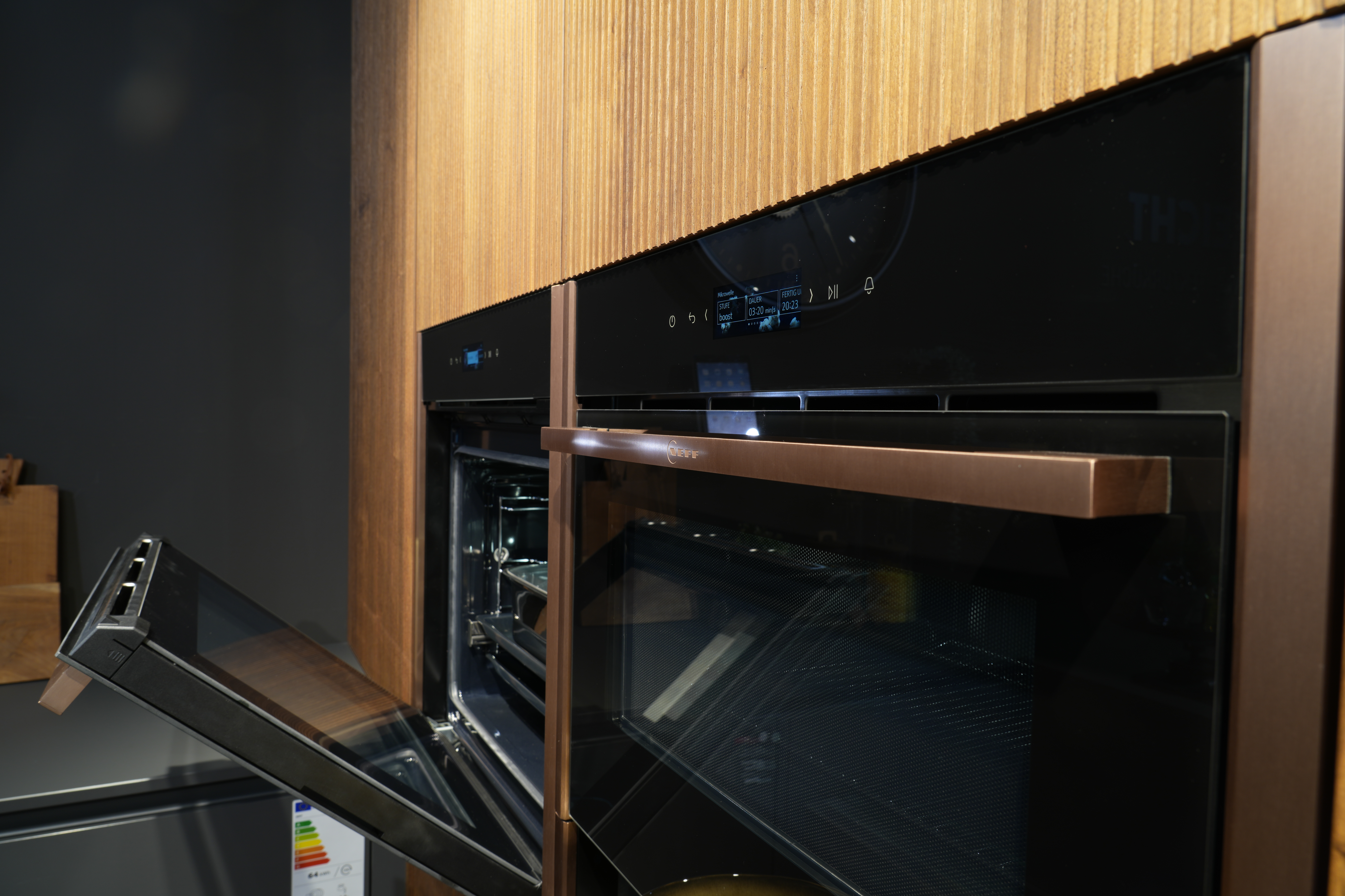 Moderner Küchenbereich mit zwei übereinander eingebauten Backöfen, einer davon geöffnet.