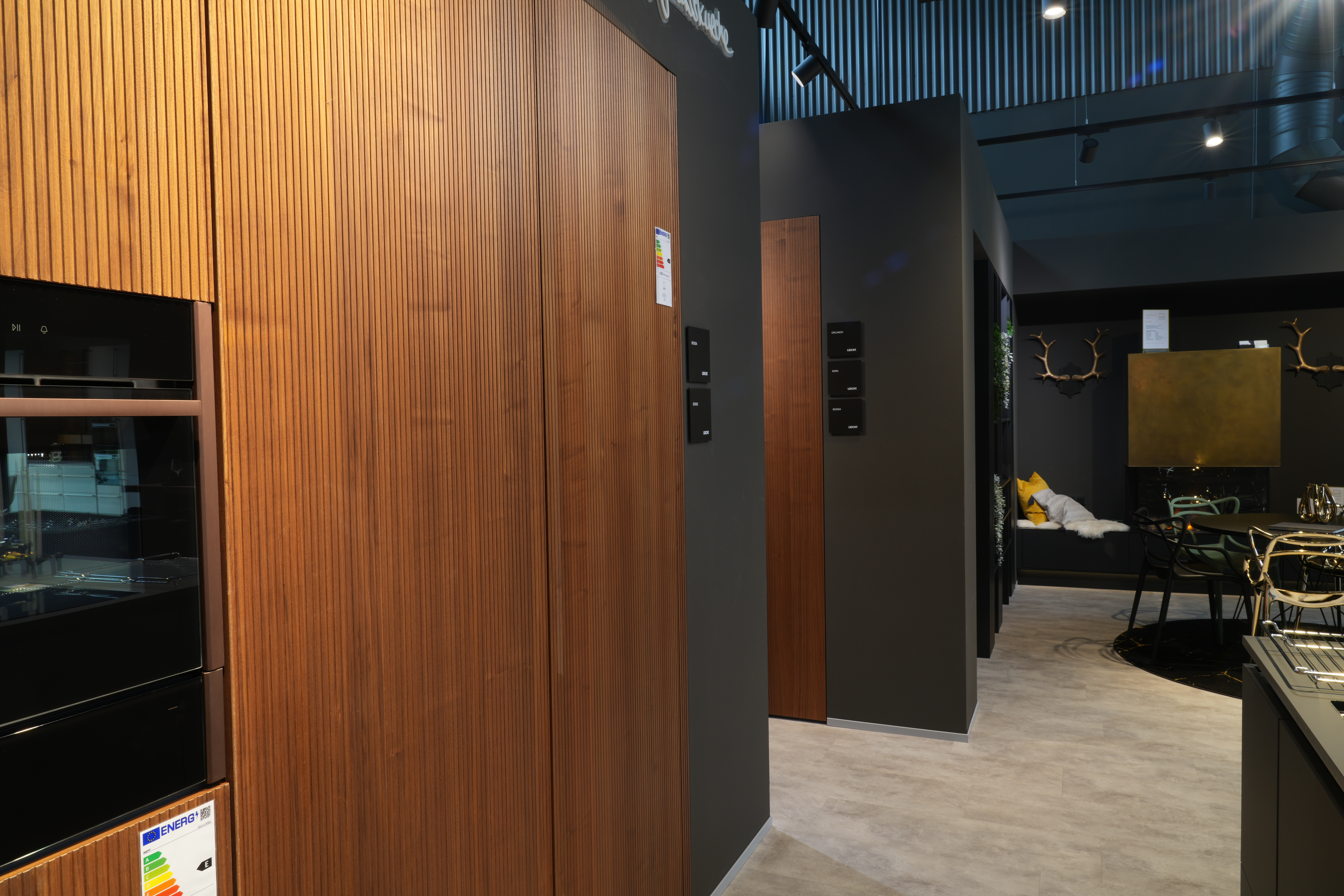 Moderner Küchenraum mit Holzschränken, eingebautem Ofen und gemütlichem Sitzbereich.