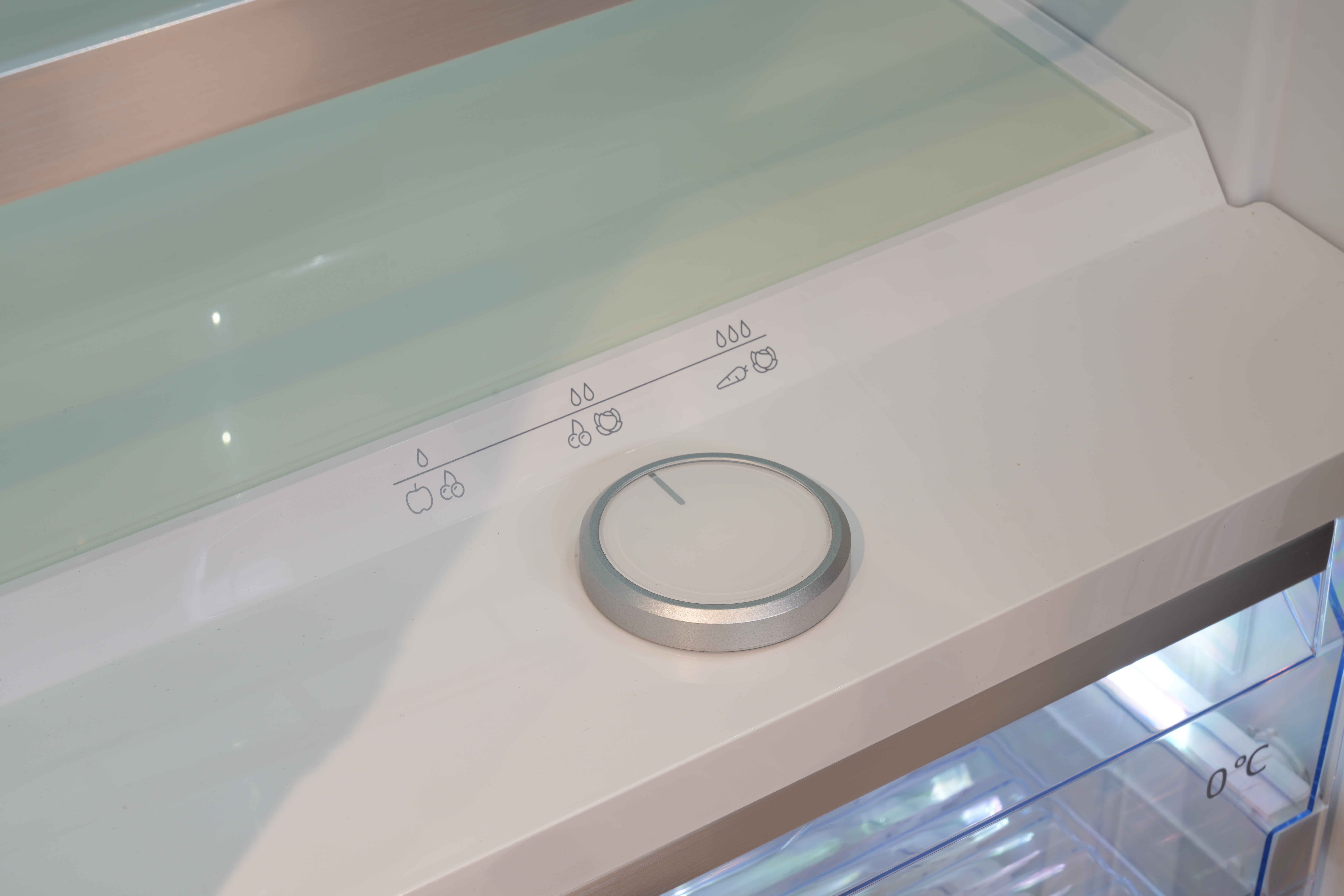 Innenraum eines Kühlschranks mit Drehregler zur Feuchtigkeitsanpassung für Obst und Gemüse.