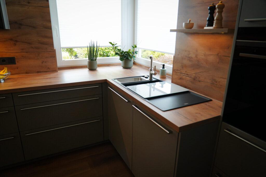 Moderne, minimalistische Küche mit Holzarbeitsplatte, Pflanzen und natürlicher Beleuchtung.