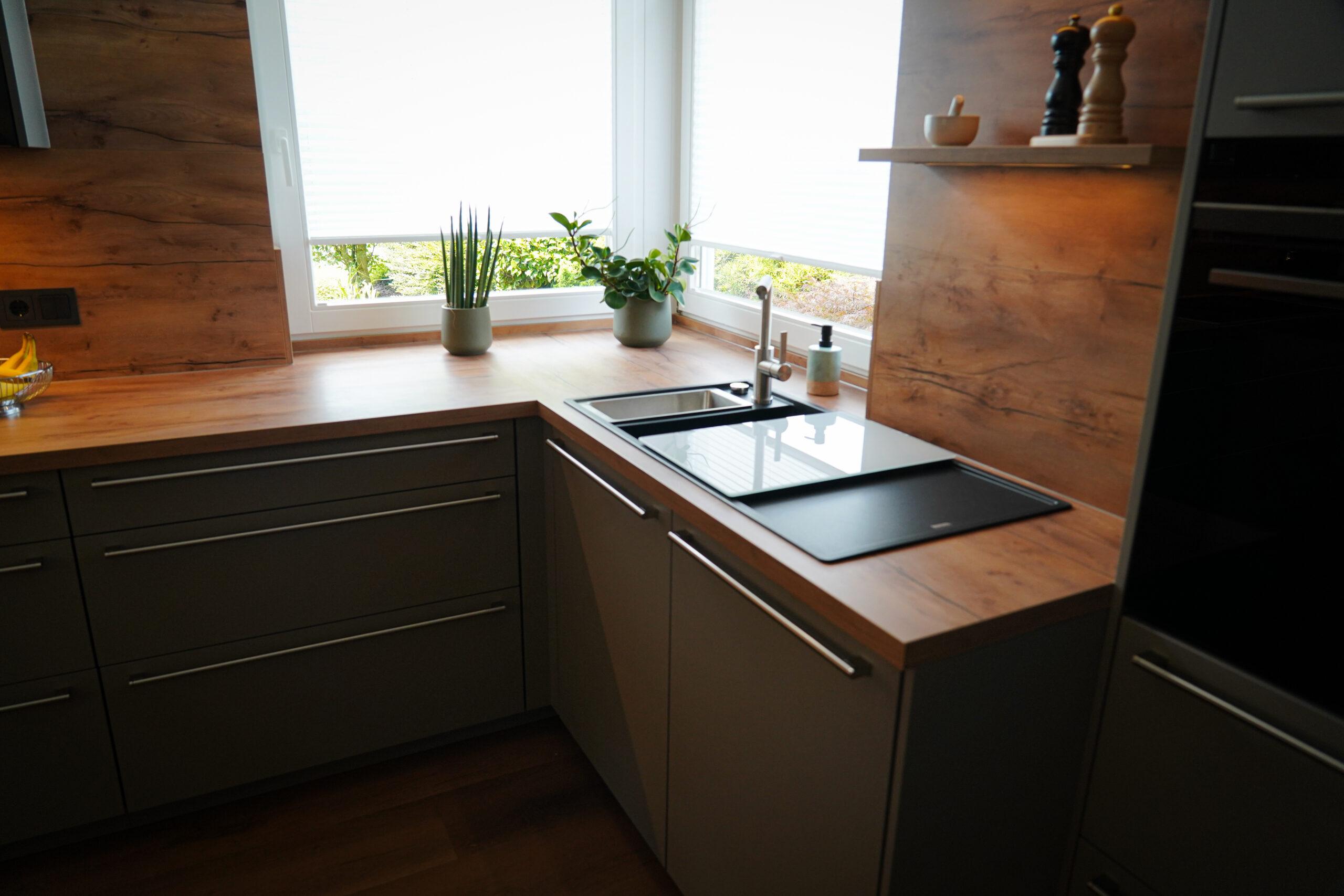 Moderne, minimalistische Küche mit Holzarbeitsplatte, Pflanzen und natürlicher Beleuchtung.