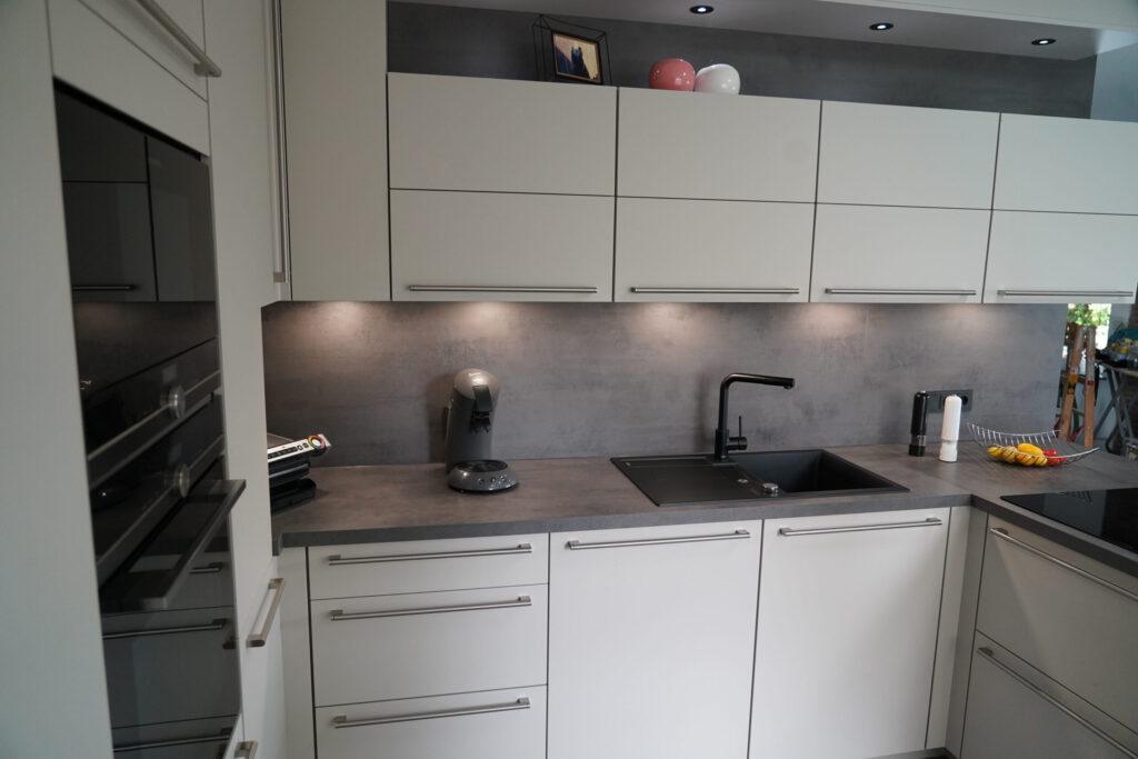 Moderne, minimalistische Küche in neutralen Tönen mit Obstkorb und dekorativen Vasen.