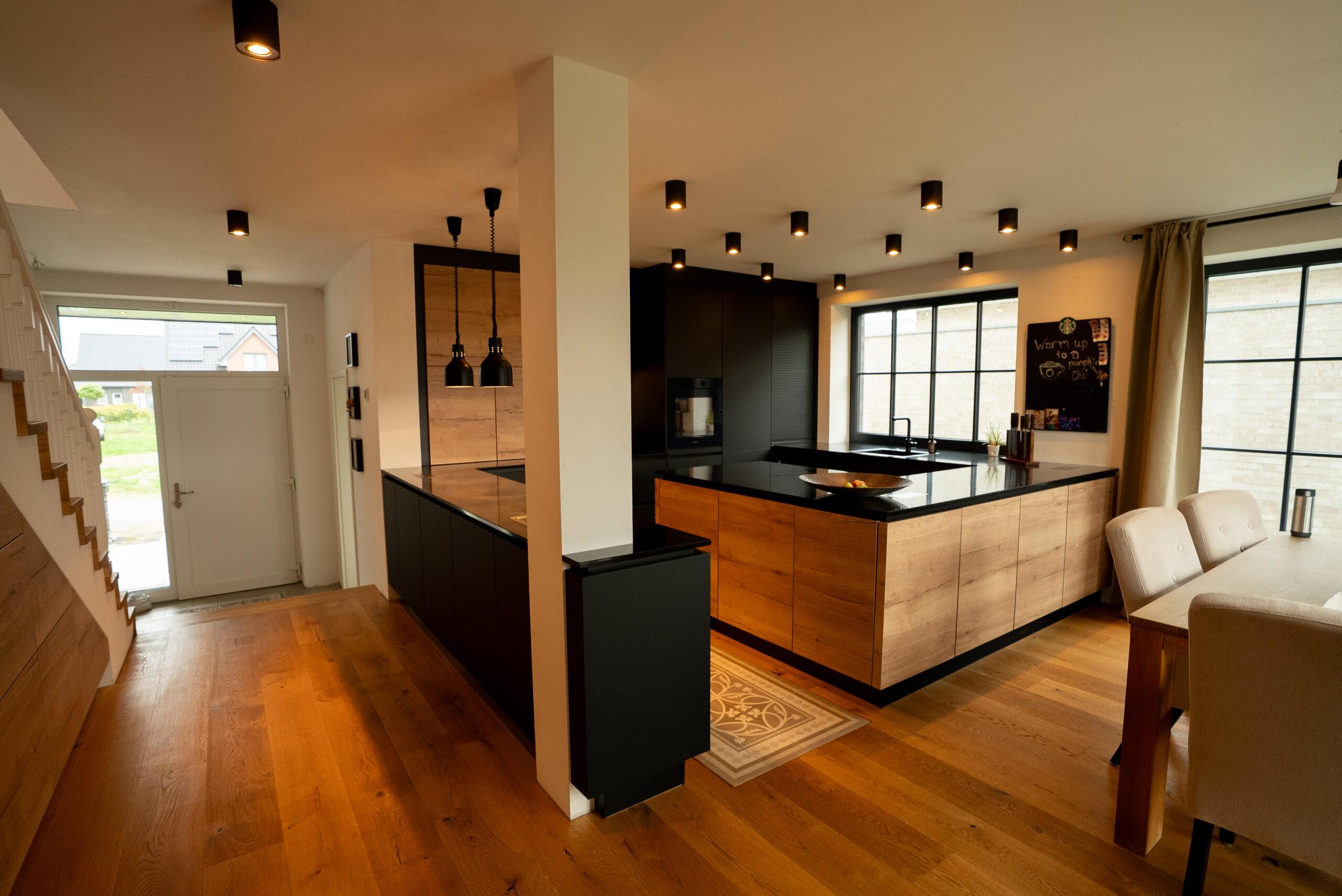 Moderner Wohnbereich mit Holz- und Schwarztönen, offener Küche und Essbereich, warm und einladend.