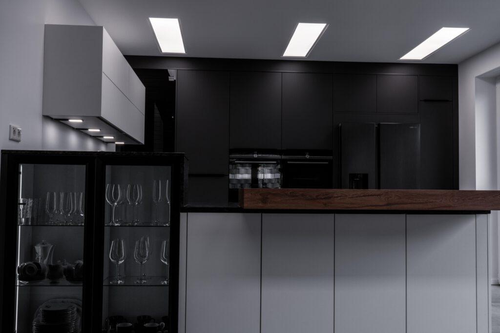 Moderne, aufgeräumte Küche mit dunklen Farben, Holzakzenten und eleganten, glatten Oberflächen.