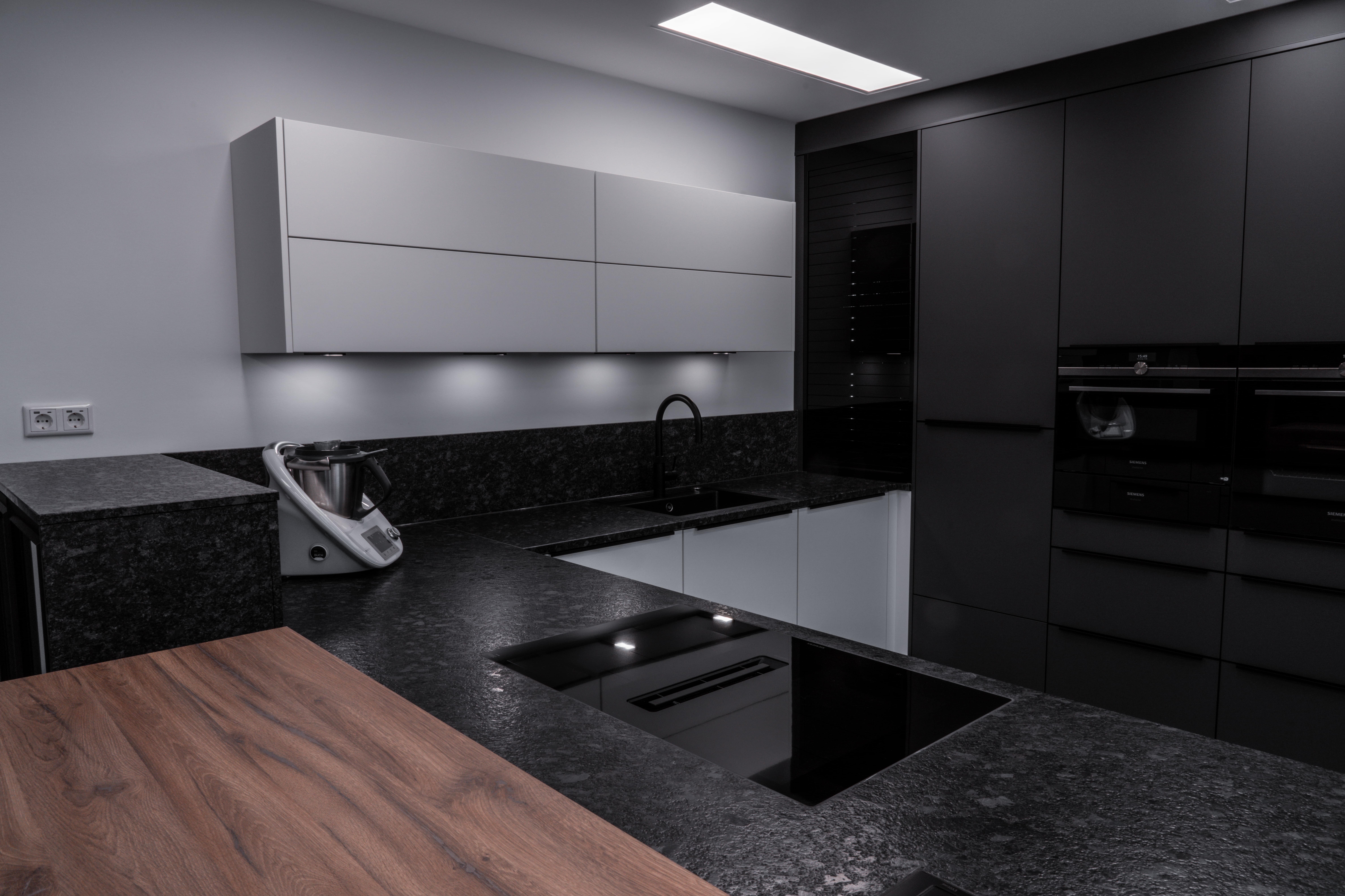 Moderne, minimalistische Küche in neutralen Tönen mit schwarzem Spülbecken und Holzarbeitsplatte.