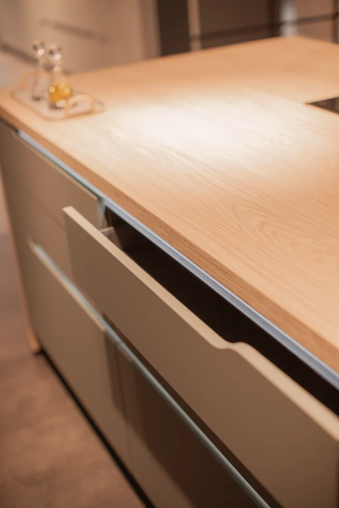 Moderne Küche mit Holzarbeitsplatte, offenen Schubladen und dekorativem Tablett mit Gläsern.