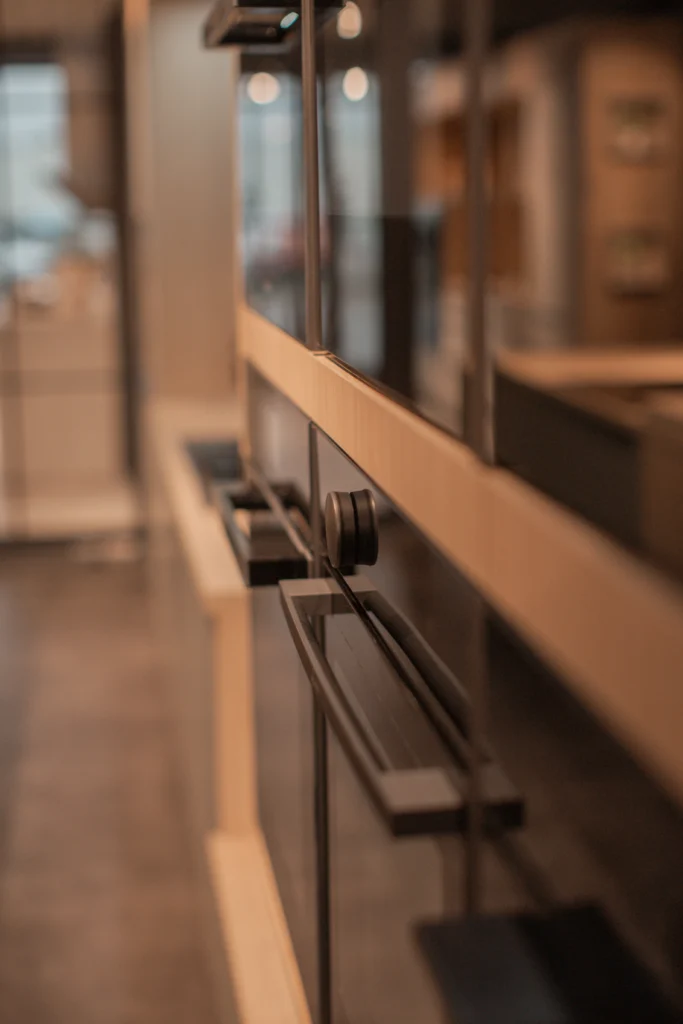 Moderner Küchenbereich mit glänzendem, schwarzem Einbaugerät und warmen Holzdetails.