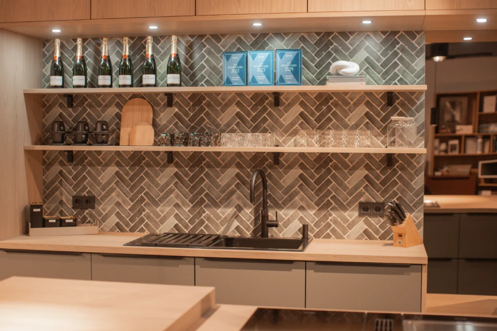 Moderne Küche mit Holzregalen, Champagnerflaschen, Auszeichnungen, Gläsern und einer schwarzen Spüle.