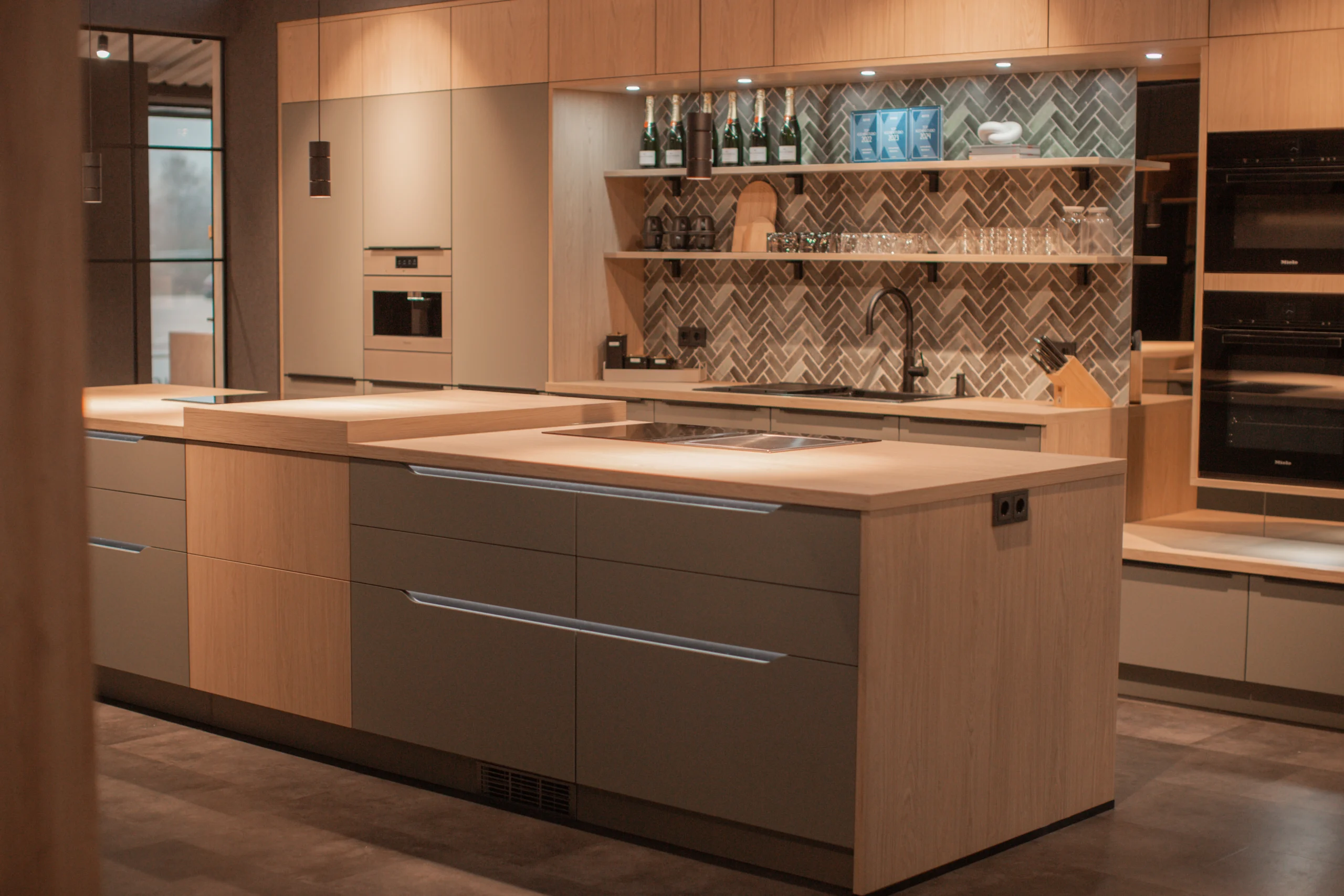 Moderne Küche mit minimalistischer Einrichtung, großer Insel, Einbaugeräten und warmen Holztönen.