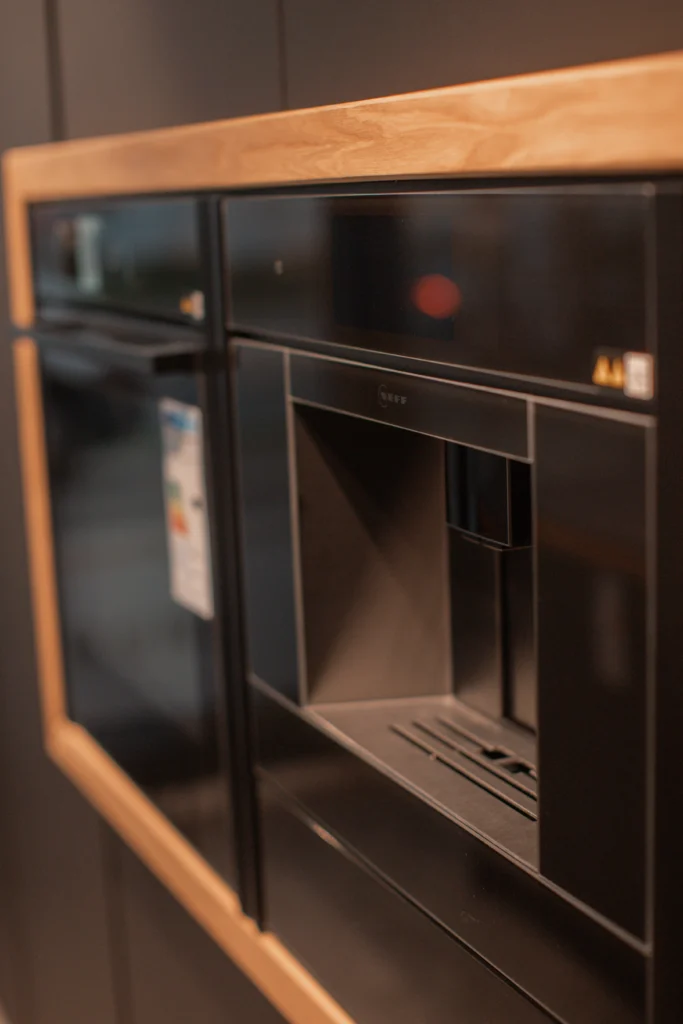 Ein moderner, in Holzrahmen eingebauter Kaffeevollautomat in einer stilvollen, eleganten Küche.