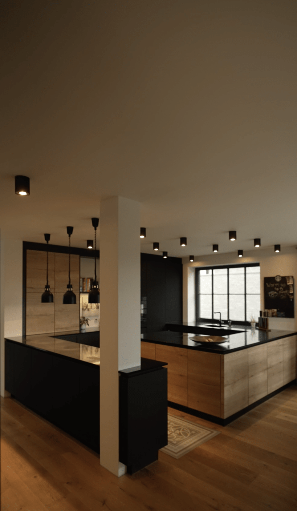 Moderne Küche mit schwarzer Insel, Holzschränken, großen Fenstern und hängenden Pendelleuchten.