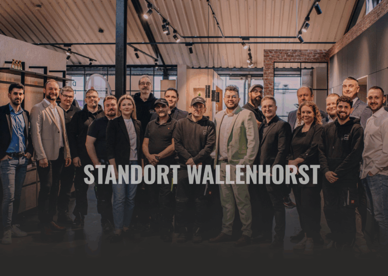 Eine Gruppe von Menschen posiert lächelnd in einem modernen, industriellen Innenraum für ein Foto.