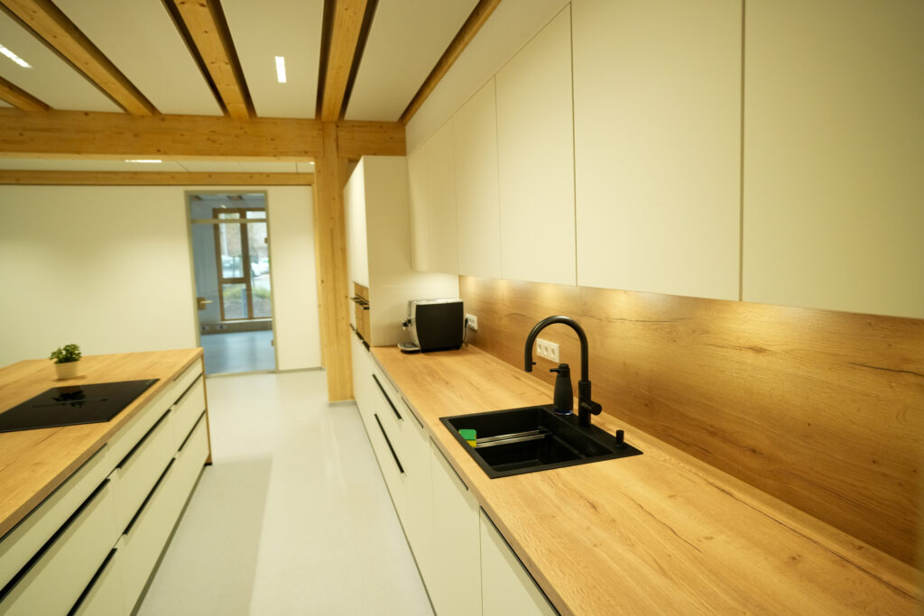 Moderne Küche mit hellen Schränken, Holzarbeitsplatte, schwarzem Waschbecken und Kücheninsel.