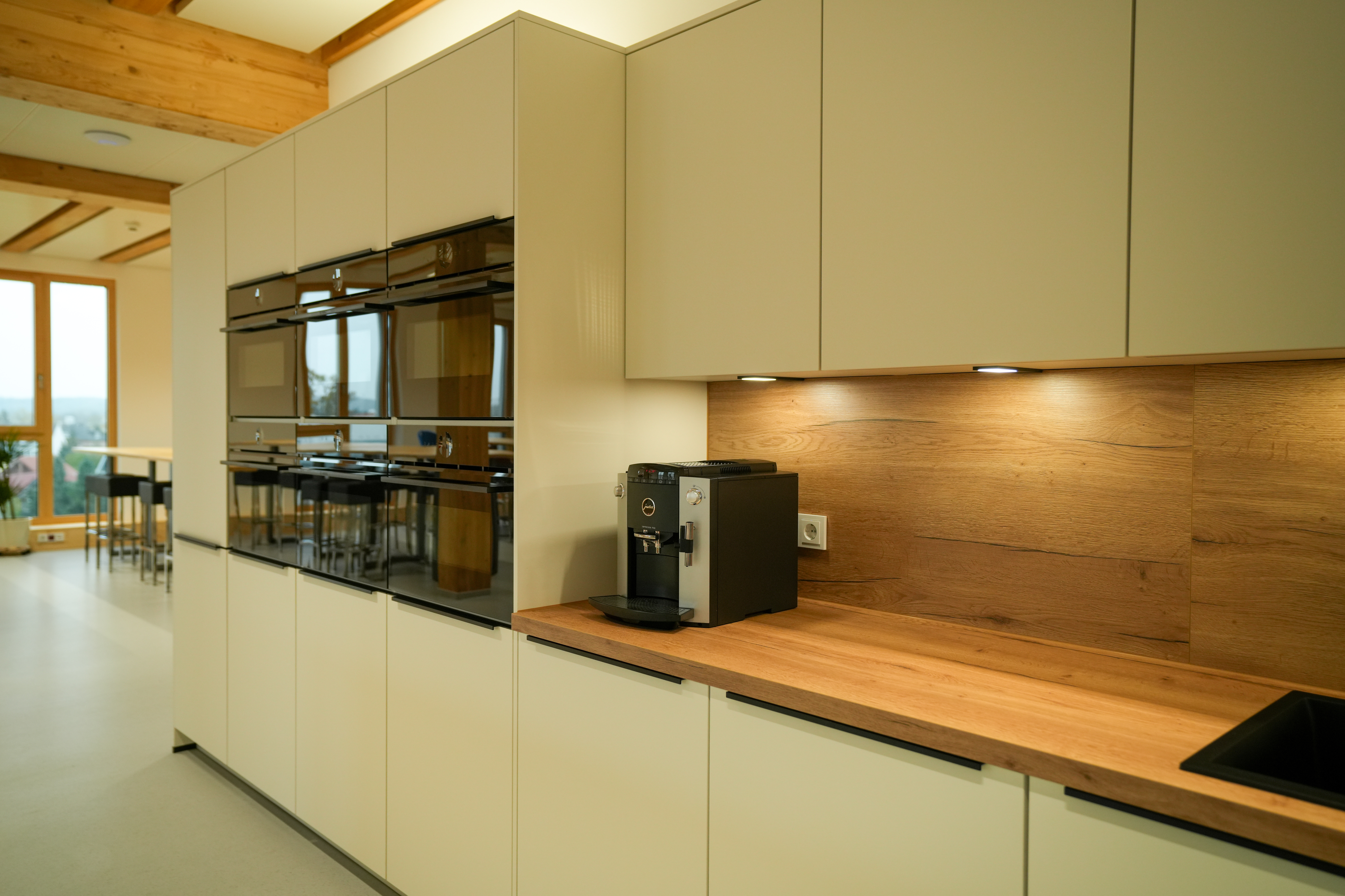 Moderne, minimalistische Küche mit hellen Schränken, Holzarbeitsplatte und eingebauten Elektrogeräten.