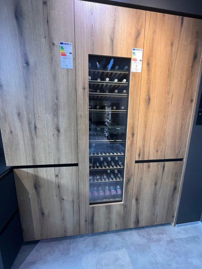 Moderner Weinkühlschrank mit Glastür, in Holzverkleidung integriert, zeigt gelagerte Weinflaschen.