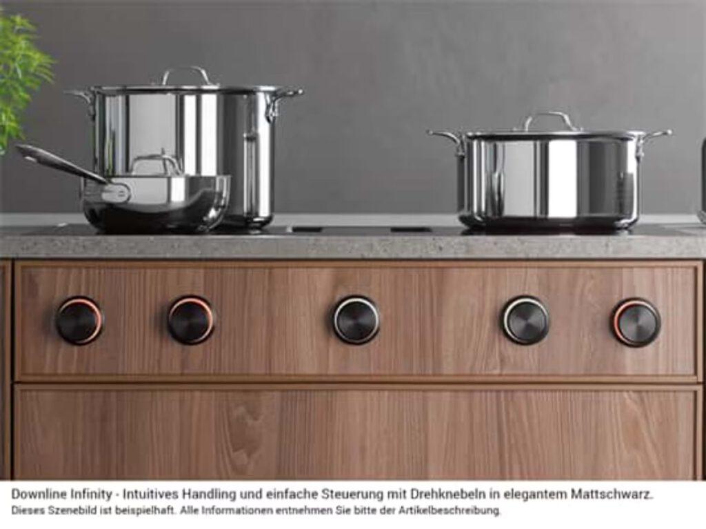 Moderne Küche mit glänzenden Edelstahltöpfen auf einem eleganten Kochfeld mit schwarzen Drehknöpfen.