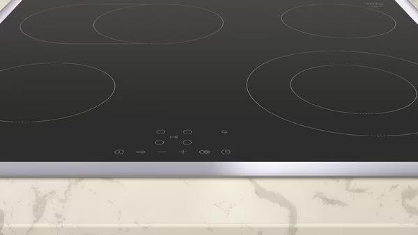 Moderne Induktionskochplatte mit schwarzer, glatter Oberfläche und silbernem Rand auf marmorierter Arbeitsplatte.