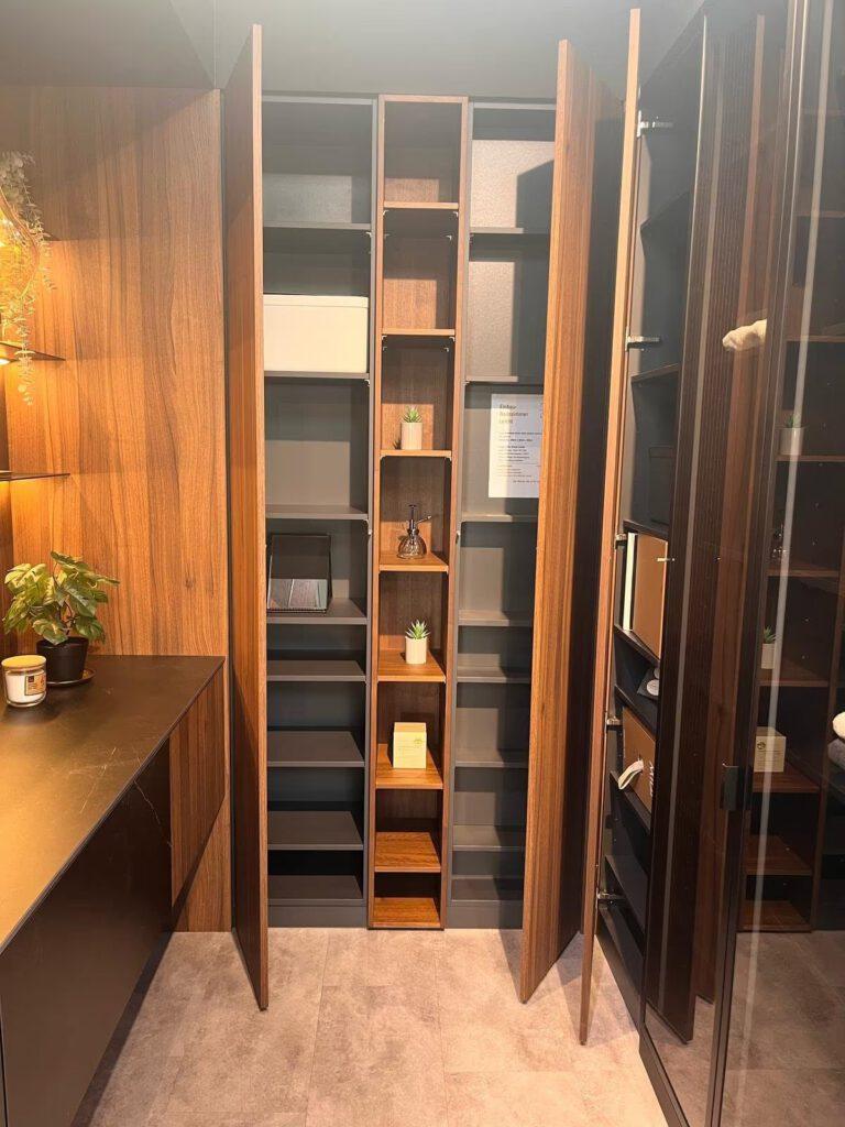 Moderner Schrankbereich mit warmen Holztönen, offenen Regalen und dekorativen Elementen.