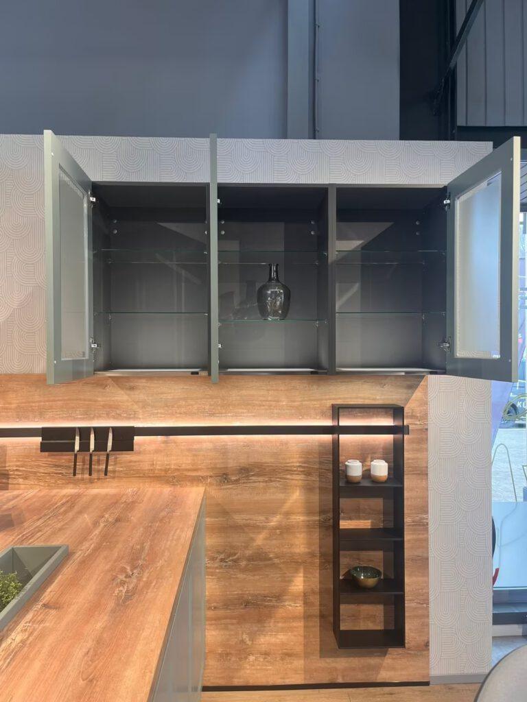 Moderne Küche mit Holzarbeitsplatte, offenen grauen Schränken und einem Messerblock an der Wand.