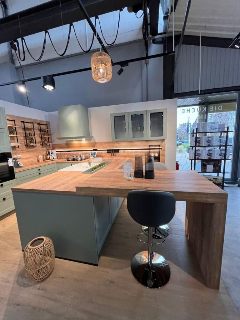 Moderne Küche mit grünen Schränken, Holzarbeitsplatte, zentraler Insel und verchromtem Stuhl.