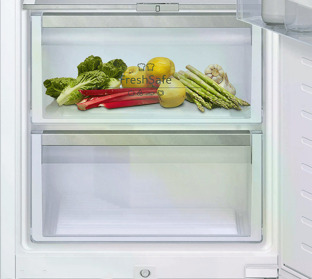 Ein Kühlschrankfach mit frischem Gemüse und Obst: Römersalat, Zitronen, Rhabarber, Spargel und Knoblauch.