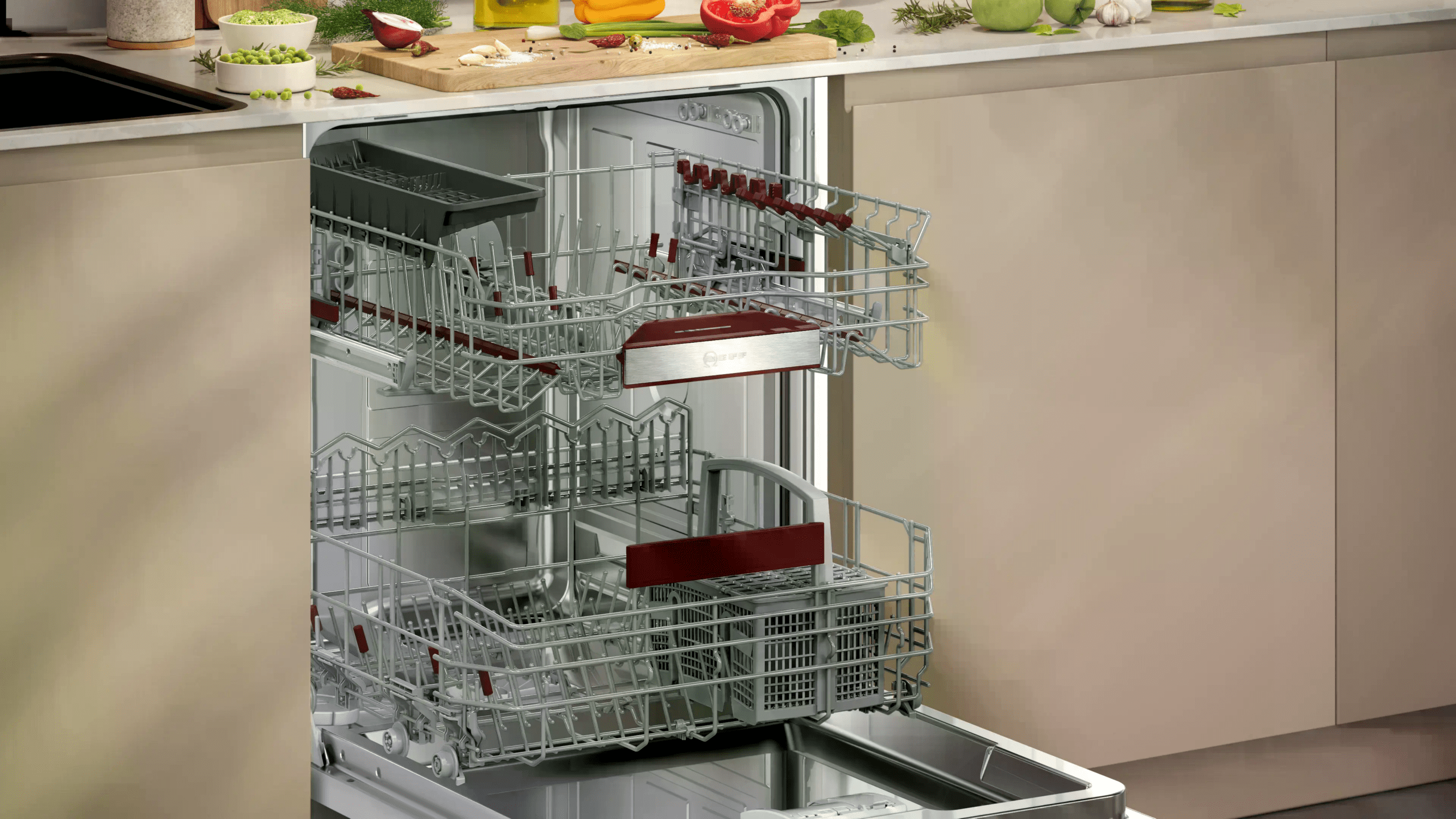 Offene Spülmaschine in moderner Küche, umgeben von buntem Gemüse und Utensilien auf der Arbeitsplatte.