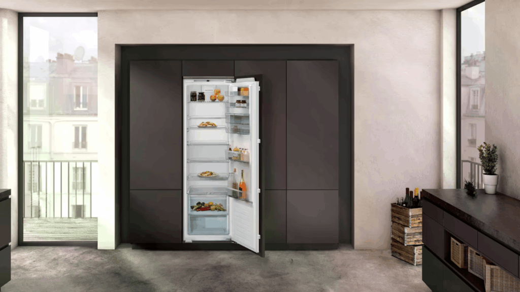 Moderne Küche mit offenem Einbaukühlschrank, gefüllt mit Lebensmitteln, in dunkler Schrankwand integriert.