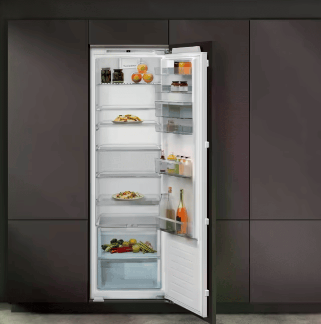 Moderne Küche mit offenem Einbaukühlschrank, gefüllt mit Lebensmitteln, in dunkler Schrankwand integriert.