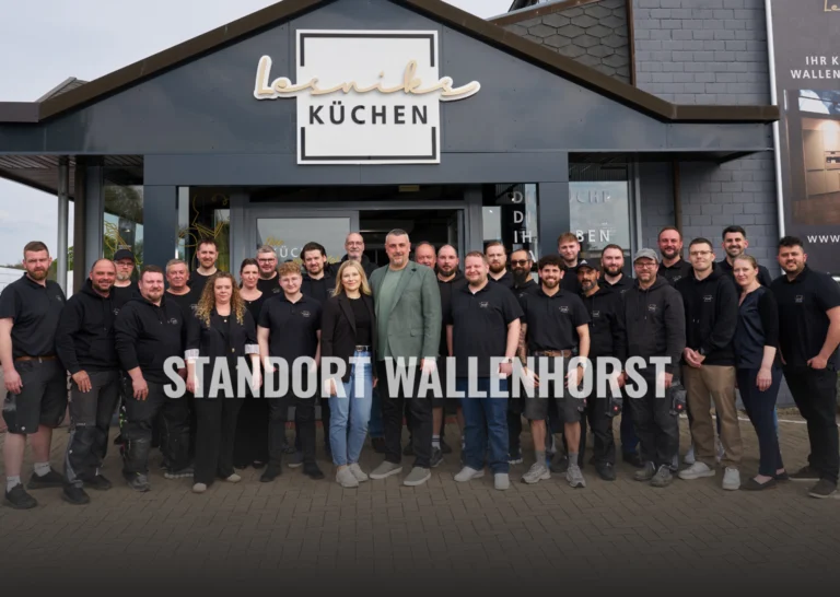 Teamfoto vor modernem Gebäude mit „Lesniak Küchen“ Schild, Personen lächeln freundlich.