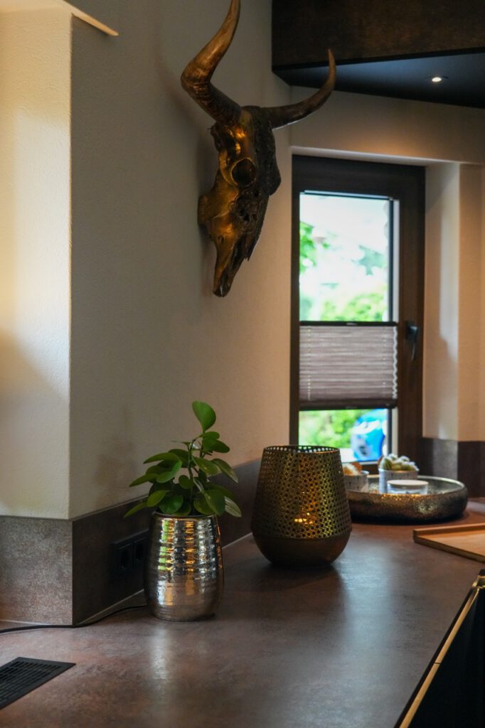 Ein goldener Stierschädel an der Wand, mit Pflanze und Kerzenhalter auf einer stilvollen Arbeitsfläche.