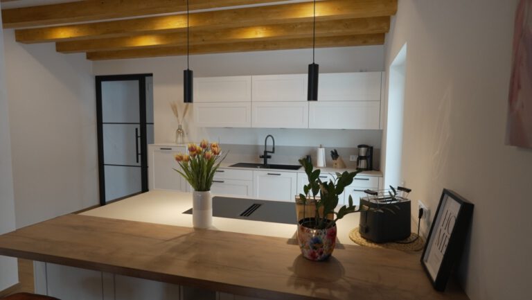 Moderne Küche mit weißer Einrichtung, Holzarbeitsfläche, Blumenvasen und schwarzen Akzenten.